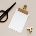 composition of scissors and clip around clipboard on table