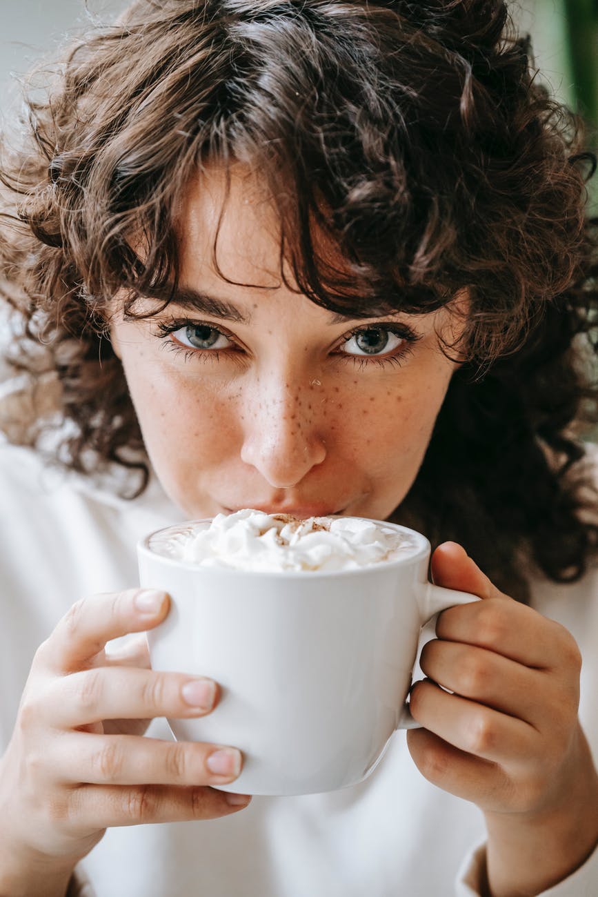 content young woman drinking sweet fragrant coffee with foam