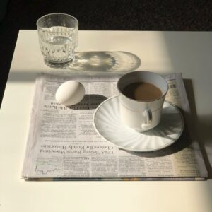 cup of coffee and boiled egg placed on morning newspaper