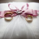 selective focus photography of silver colored engagement ring set with pink bow accent on throw pillow