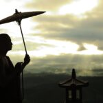 silhouette photo of monk holding umbrella