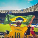 man raising brazil flag inside football stadium